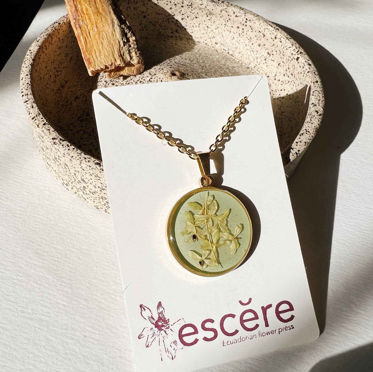 Gold pendant necklace with pressed flower on turquoise background in epoxy resin on gold chain