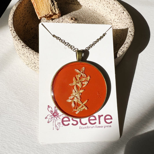 Bronze pendant necklace with pressed flowers on red orange background in epoxy resin on bronze chain