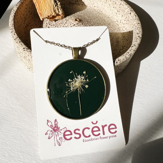 Bronze pendant necklace with pressed flowers on dark green background in epoxy resin on bronze chain