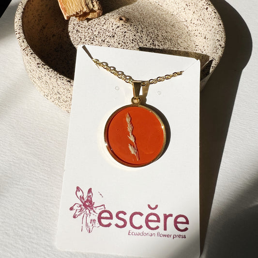 Gold pendant necklace with pressed flower grass on red orange background in epoxy resin on gold chain
